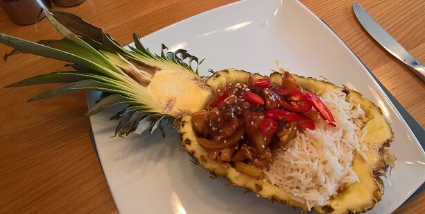 Sticky pineapple chicken, served in a carved out half pineapple